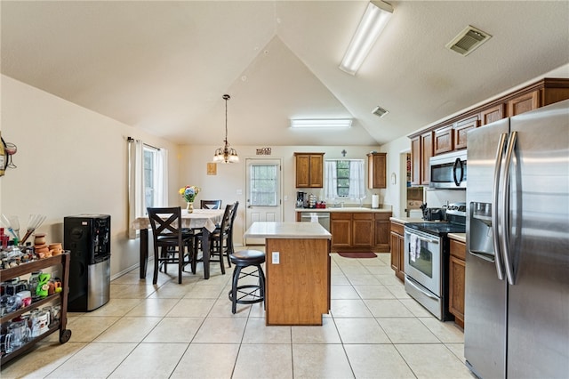 kitchen featuring appliances with stainless steel finishes, a kitchen bar, hanging light fixtures, a center island, and light tile patterned floors