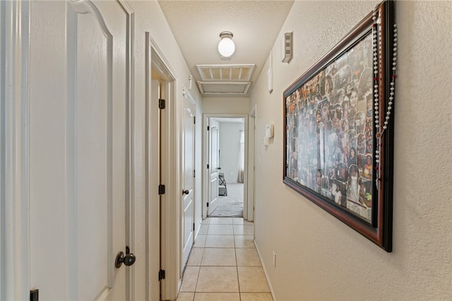 corridor featuring light tile patterned floors and a textured ceiling