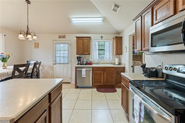 kitchen featuring pendant lighting, sink, lofted ceiling, appliances with stainless steel finishes, and light tile patterned flooring