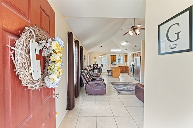 tiled foyer entrance with ceiling fan with notable chandelier and lofted ceiling