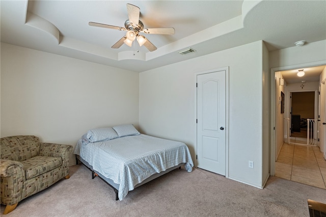 carpeted bedroom with ceiling fan and a raised ceiling