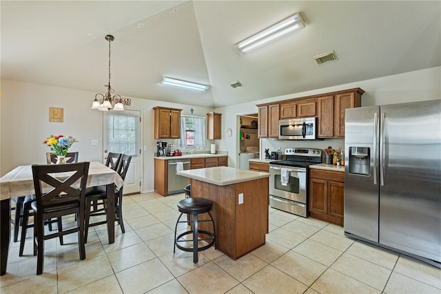 kitchen with stainless steel appliances, hanging light fixtures, a kitchen island, and light tile patterned floors