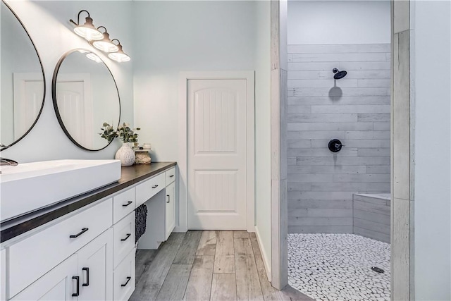 bathroom featuring vanity, wood-type flooring, and tiled shower