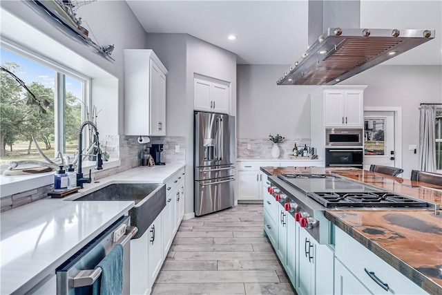 kitchen with white cabinetry, stainless steel appliances, decorative backsplash, and island range hood