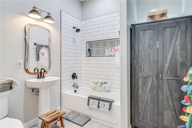 bathroom featuring tiled shower / bath combo and toilet