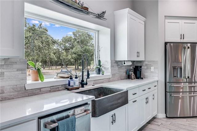 kitchen with sink, light hardwood / wood-style flooring, backsplash, stainless steel appliances, and white cabinets