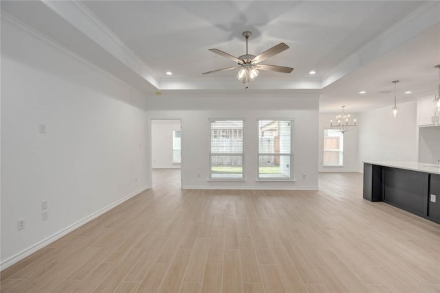 unfurnished living room featuring ceiling fan with notable chandelier, crown molding, light hardwood / wood-style flooring, and a tray ceiling