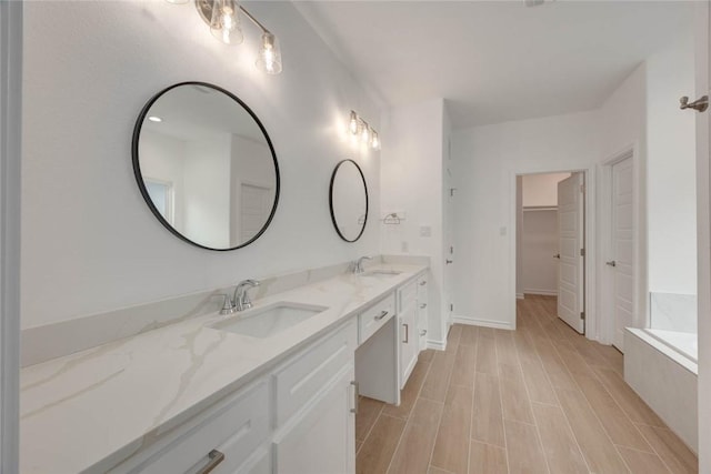 bathroom with vanity and tiled tub