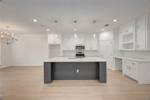 kitchen with a kitchen island with sink, white cabinetry, pendant lighting, and stainless steel appliances