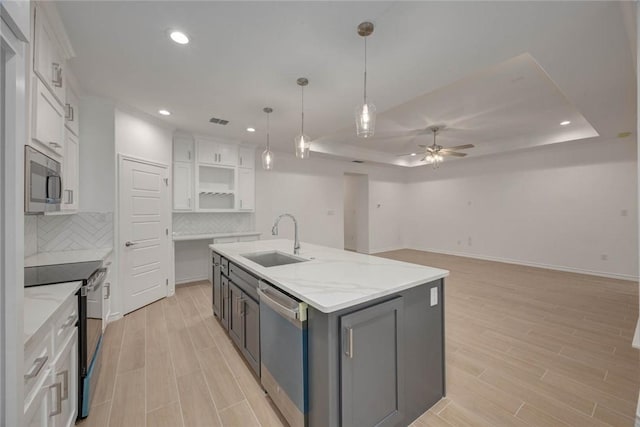 kitchen with white cabinets, a center island with sink, sink, and appliances with stainless steel finishes