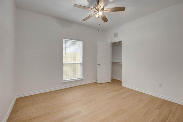 unfurnished bedroom featuring ceiling fan, light hardwood / wood-style floors, a spacious closet, and a closet