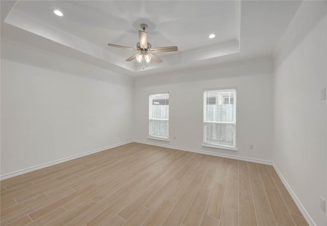 spare room with a raised ceiling, ceiling fan, light hardwood / wood-style flooring, and crown molding