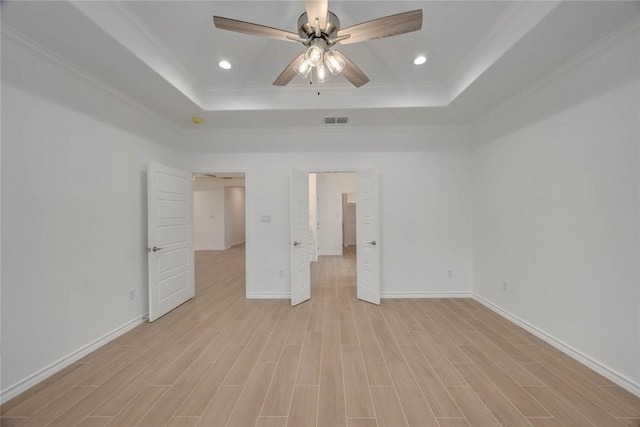 unfurnished bedroom with a raised ceiling, ceiling fan, crown molding, and light hardwood / wood-style floors