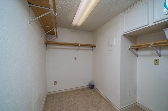 washroom with baseboards, cabinet space, and a textured ceiling