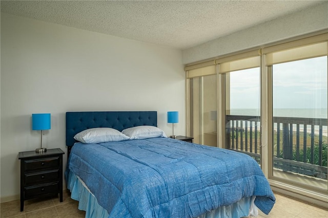 bedroom with tile patterned floors, a textured ceiling, and access to outside