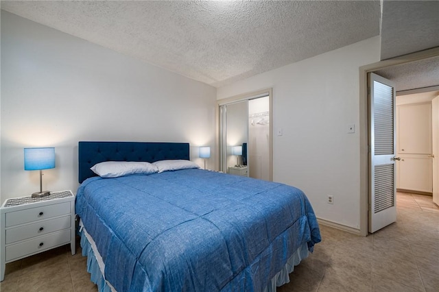 bedroom with tile patterned flooring, baseboards, and a textured ceiling