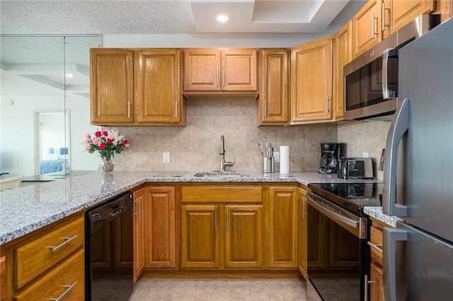 kitchen featuring a sink, stainless steel appliances, light stone counters, and decorative backsplash