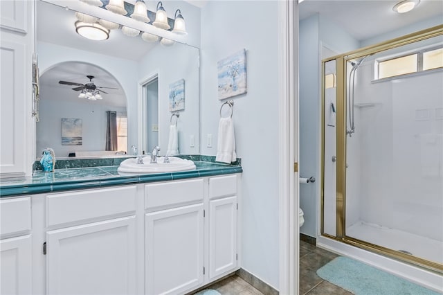 bathroom with ceiling fan, tile patterned flooring, toilet, a shower with door, and vanity