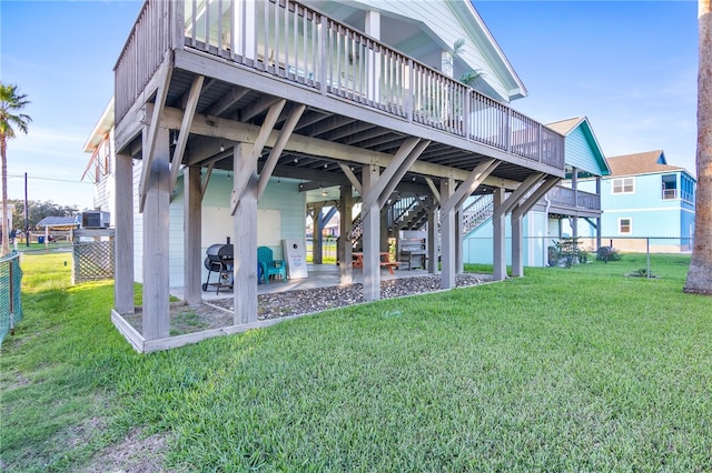 back of property featuring a patio, a wooden deck, and a lawn