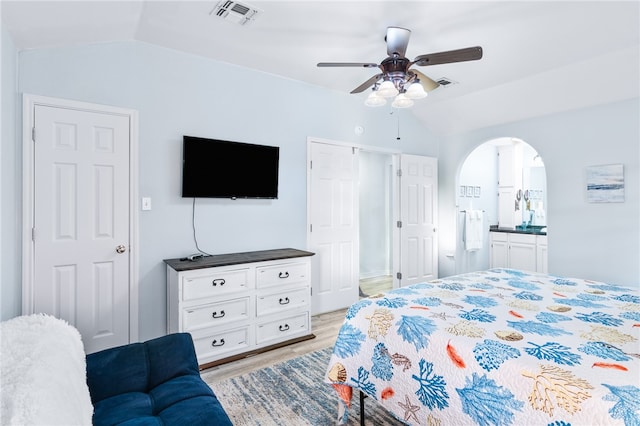 bedroom with vaulted ceiling, ensuite bath, light hardwood / wood-style flooring, and ceiling fan