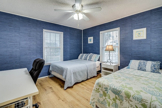 bedroom with multiple windows, ceiling fan, hardwood / wood-style floors, and a textured ceiling