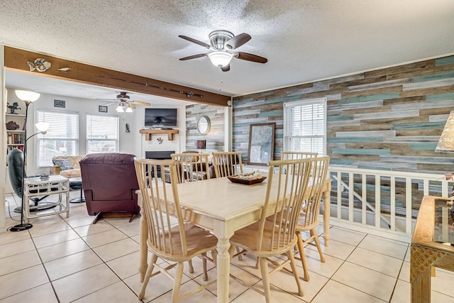 tiled dining space with beam ceiling, a textured ceiling, a wealth of natural light, and wood walls