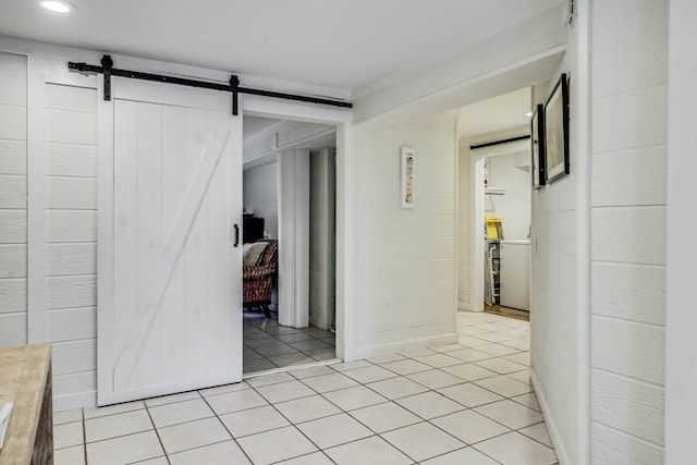 hall featuring a barn door and light tile patterned floors