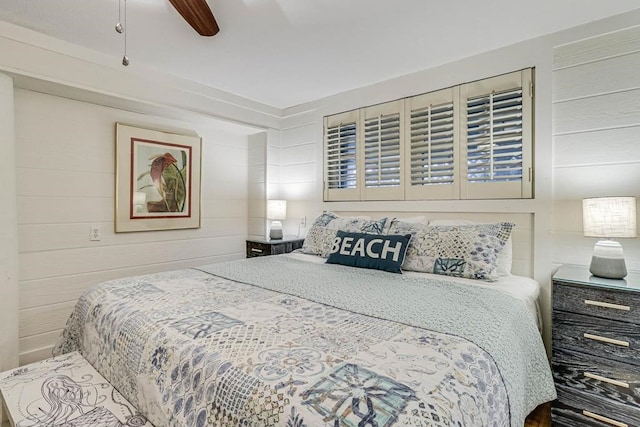 bedroom with ceiling fan and wooden walls