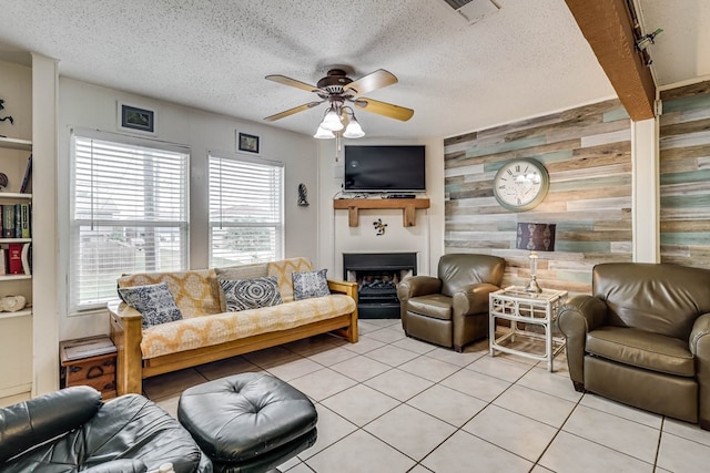 living room featuring ceiling fan, light tile patterned floors, a textured ceiling, and wooden walls