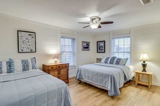 bedroom with multiple windows, ceiling fan, and light hardwood / wood-style floors