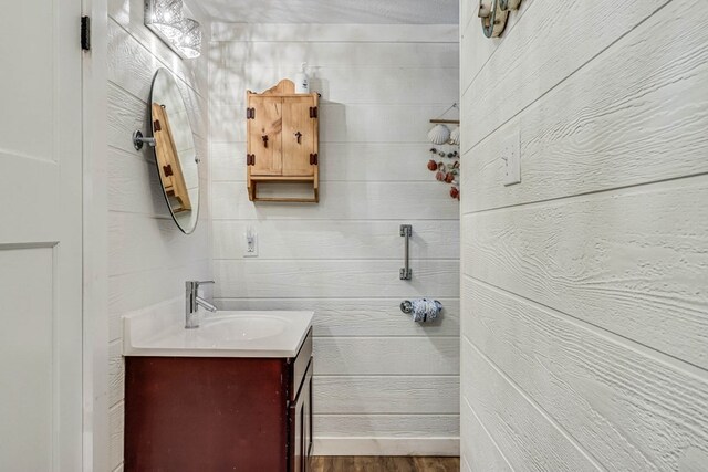 bathroom with wood walls, vanity, and wood-type flooring