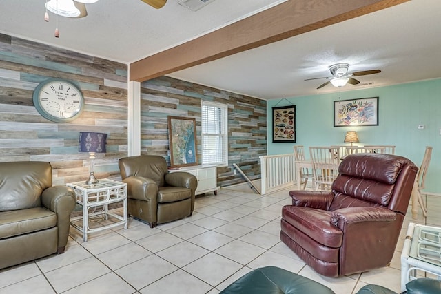 tiled living room with a textured ceiling, ceiling fan, wood walls, and beam ceiling