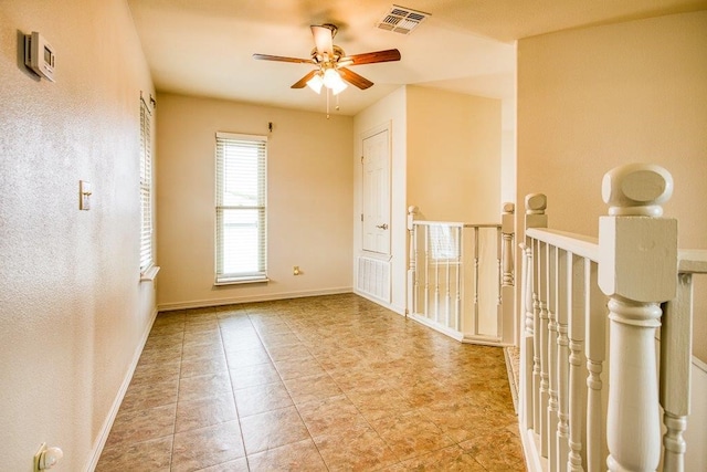 tiled empty room featuring ceiling fan