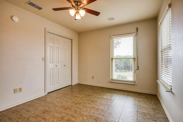 unfurnished bedroom with ceiling fan and a closet