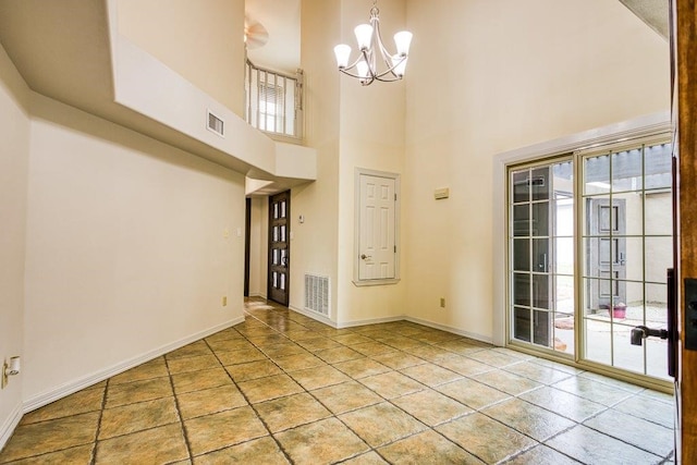 interior space featuring a high ceiling, a healthy amount of sunlight, and a notable chandelier