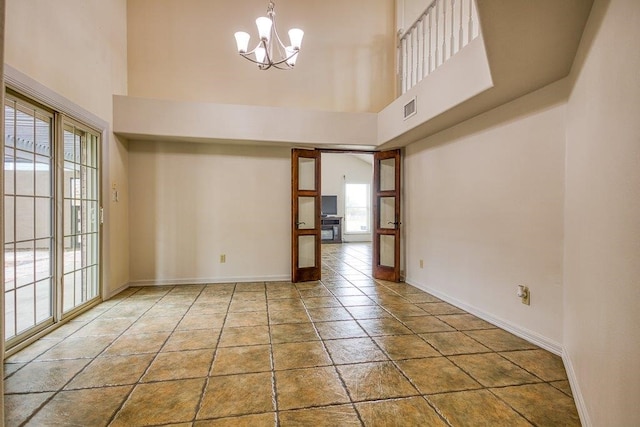 spare room featuring a high ceiling, a chandelier, and a healthy amount of sunlight