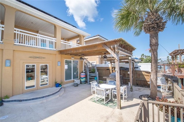 view of patio featuring a balcony, stairs, fence, outdoor dining area, and french doors