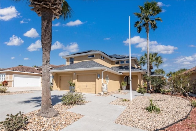 view of front of house with a garage, driveway, solar panels, and stucco siding