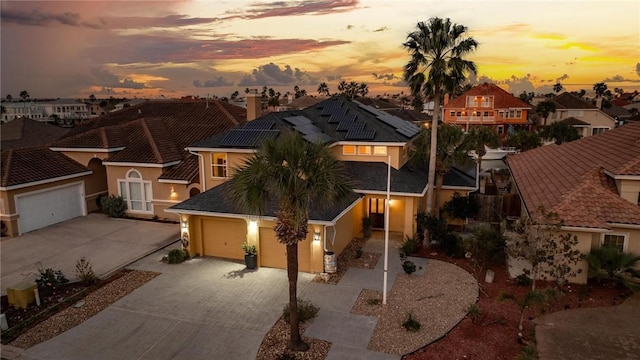 mediterranean / spanish home with a garage, a residential view, decorative driveway, and stucco siding