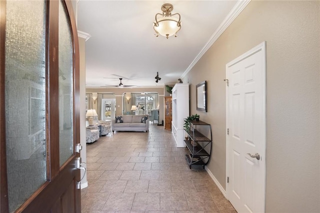 foyer entrance featuring ceiling fan, baseboards, and crown molding