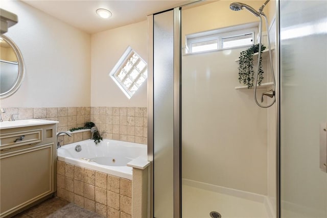 full bathroom featuring a stall shower, a garden tub, and vanity