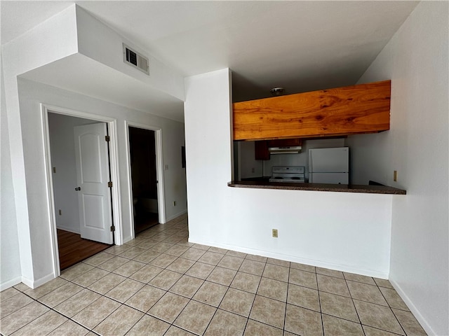 interior space with light tile patterned floors, white appliances, and ventilation hood