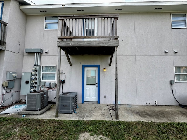 view of exterior entry with a balcony and central AC unit