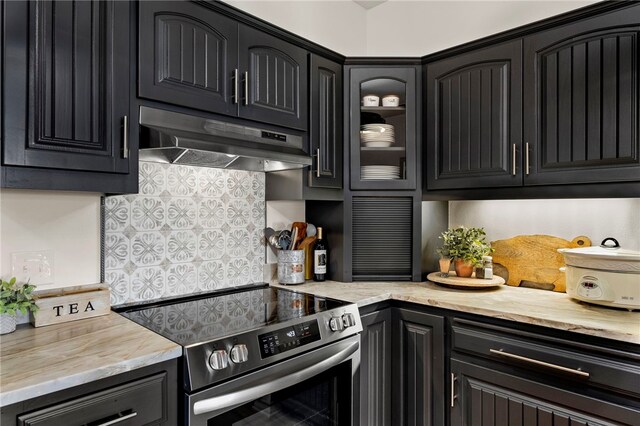1044 Edinburgh Dr Unit 1044, Kerrville, TX 78028 - kitchen featuring light stone counters, stainless steel electric stove, decorative backsplash, glass insert cabinets, and under cabinet range hood