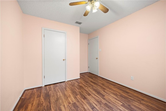 unfurnished bedroom featuring ceiling fan, dark wood-type flooring, and a textured ceiling