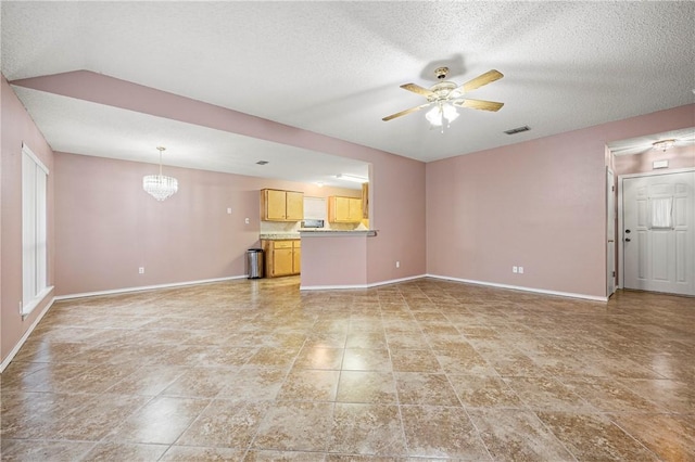 unfurnished living room with ceiling fan with notable chandelier and a textured ceiling