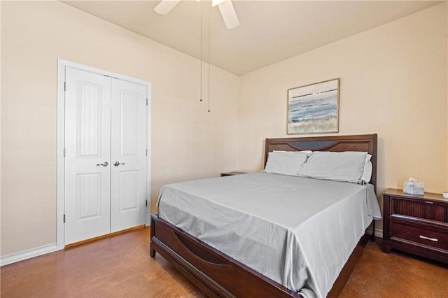 bedroom with a closet, baseboards, concrete floors, and ceiling fan