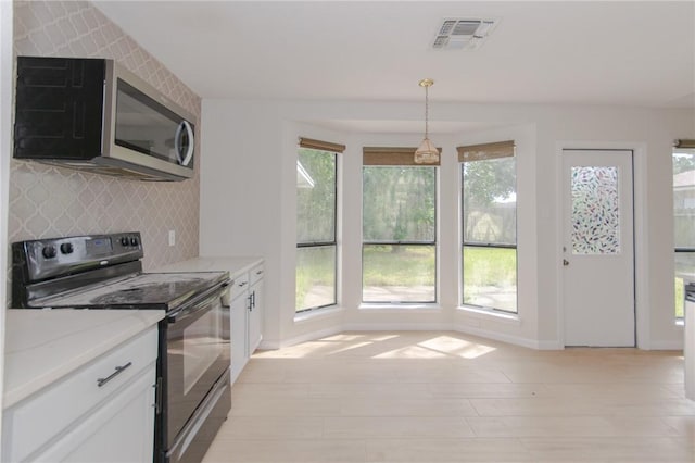 6918 Roseland Dr, Corpus Christi, TX 78414 - kitchen featuring black range with electric cooktop, stainless steel microwave, white cabinetry, decorative backsplash, and light stone countertops