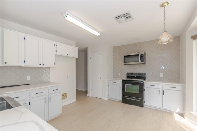 6918 Roseland Dr, Corpus Christi, TX 78414 - kitchen with black / electric stove, stainless steel microwave, tasteful backsplash, and white cabinets