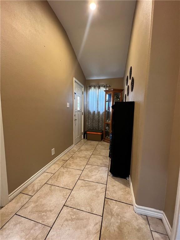 hall with light tile patterned flooring and lofted ceiling